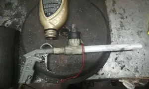 Domowy pistolet do malowania proszkowego z butelką płynu i elementami instalacji.