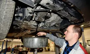 Mechanik spuszcza olej silnikowy z samochodu do miski.