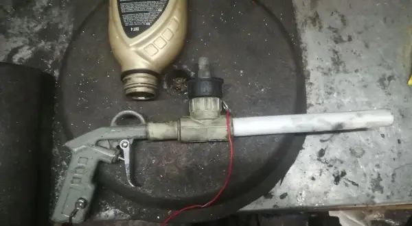 Domowy pistolet do malowania proszkowego z butelką płynu i elementami instalacji.